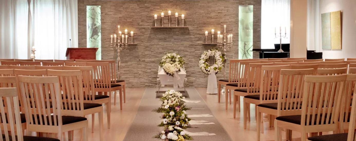 Stolrader i seremonirommet mot en vegg med levende lys og blomster