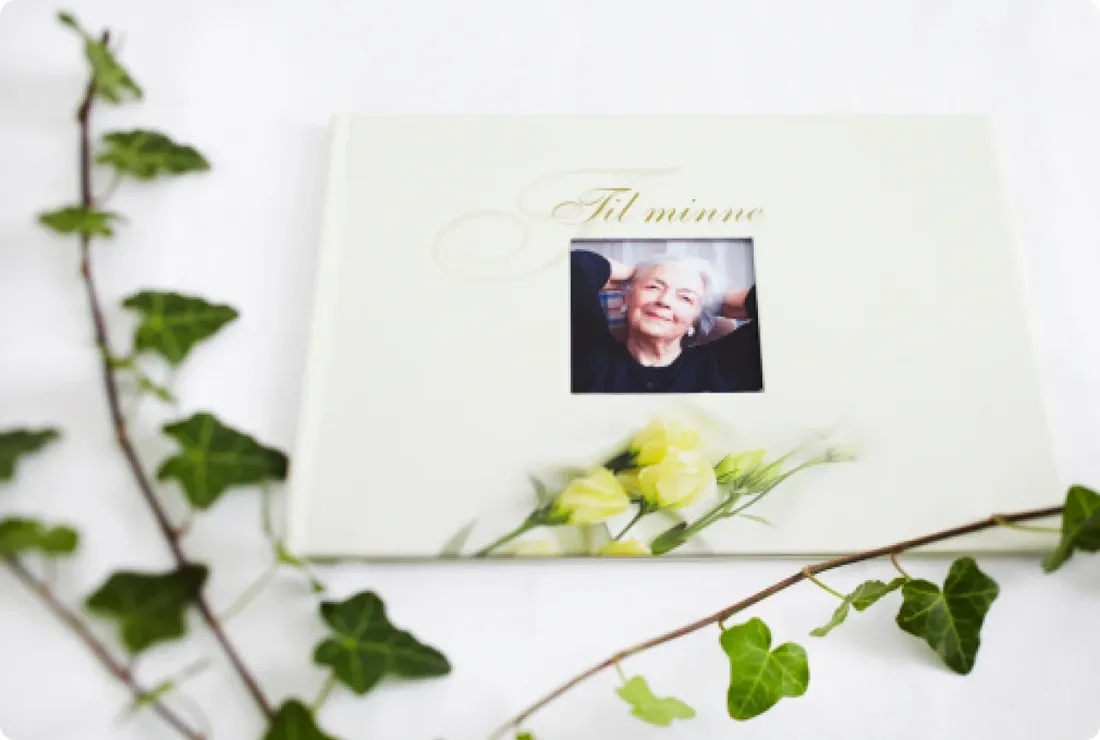 Minnebok med portrett på forsiden, pyntet med eføy og hvite blomster
